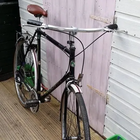 Black gents' bicycle with a green head badge, flat bars and a brown saddle