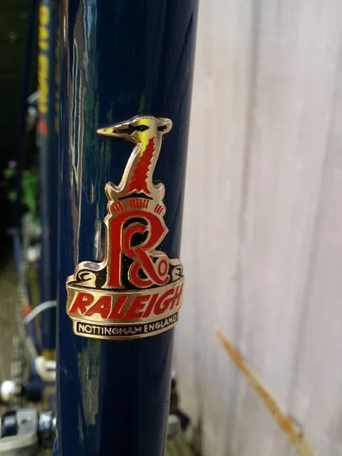 Raleigh heron head badge reading Raleigh, Nottingham England, on a blue frame