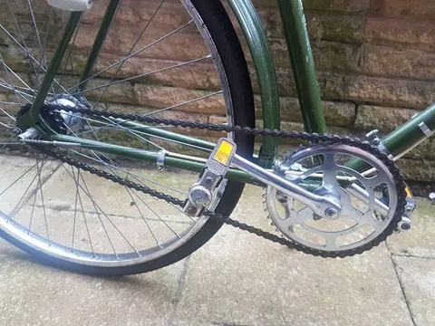 Steel chainset with a cut-out chainring and the chain, on the green Hercules