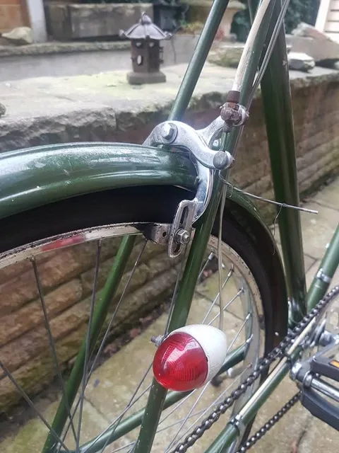 Chrome rear calliper brake and a red reflector on the green frame