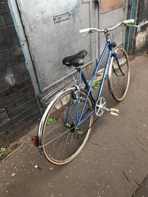 Blue Motobecane step-through bicycle with a rear rack, chrome mudguards and gumwall tyres