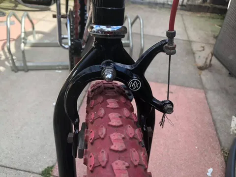 Black front brake calliper with an MX logo above a red knobbly tyre