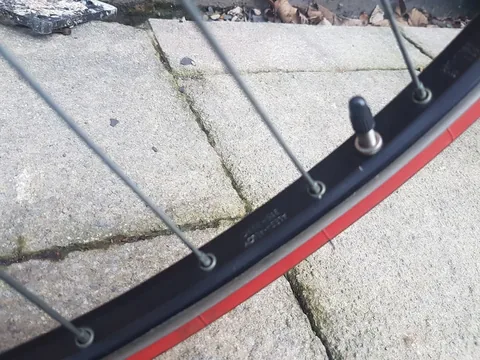 Black rim with a valve, beside a red-wall tyre