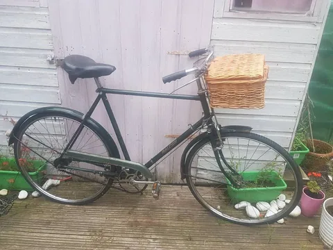 Dark green Raleigh gents' bicycle with a wicker basket on the front