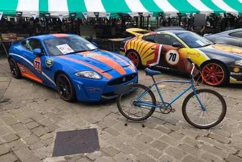 The same blue cruiser beside a blue and orange car and a yellow car