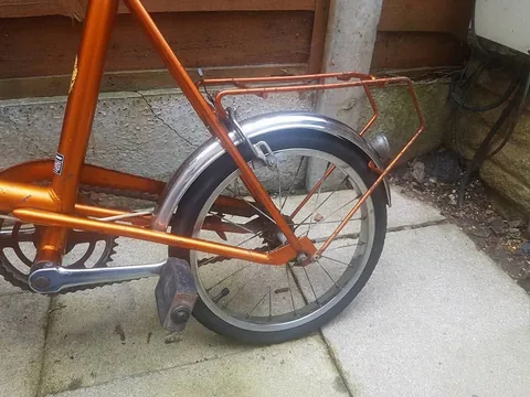 Orange rear carrier over a small rear wheel with a chrome mudguard