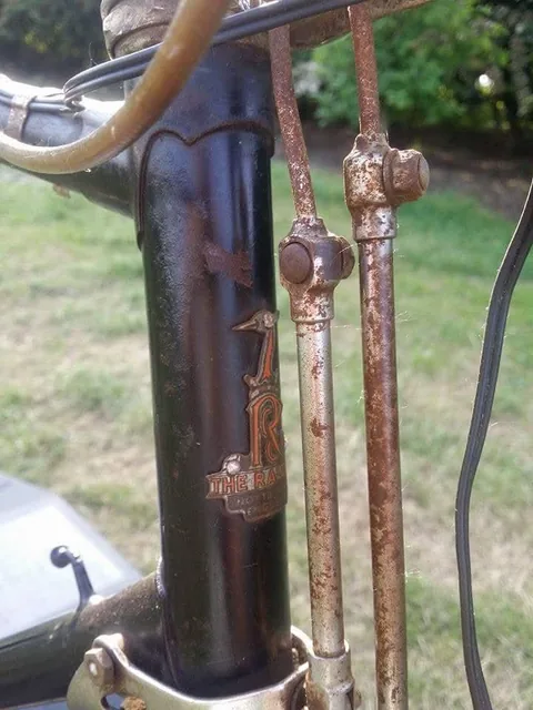 Worn Raleigh heron head badge beginning The Ra, beside rusty brake rods
